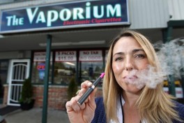 In this Tuesday May 3, 2011 picture, Kim Thompson exhales vapor from her e-cigarette outside her new business called "The Vaporium" in Lakewood, Wash. Thompson, a 20-year smoker, opened the business selling electronic cigarettes or personal vaporizers as an alternative to traditional cigarettes in January and says the business is doing well. The Tacoma-Pierce County Health Department is considering a ban on battery-powered electronic cigarettes that deliver nicotine without smoking. The News Tribune reports that regulations proposed Wednesday, May 4, 2011 would ban e-smoking _ or "vaping" _ in the same public places where the use of real cigarettes and cigars are prohibited by state law. King County adopted such a ban in January.  (AP Photo/The News Tribune, Dean J. Koepfler)